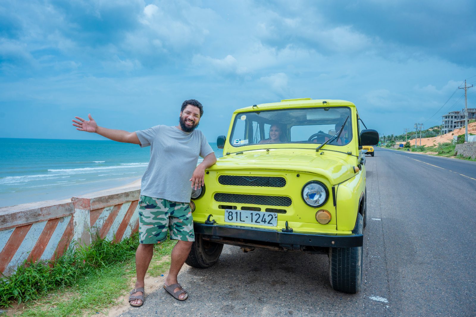 Marcellous waving hello beside the jeep on the coast road